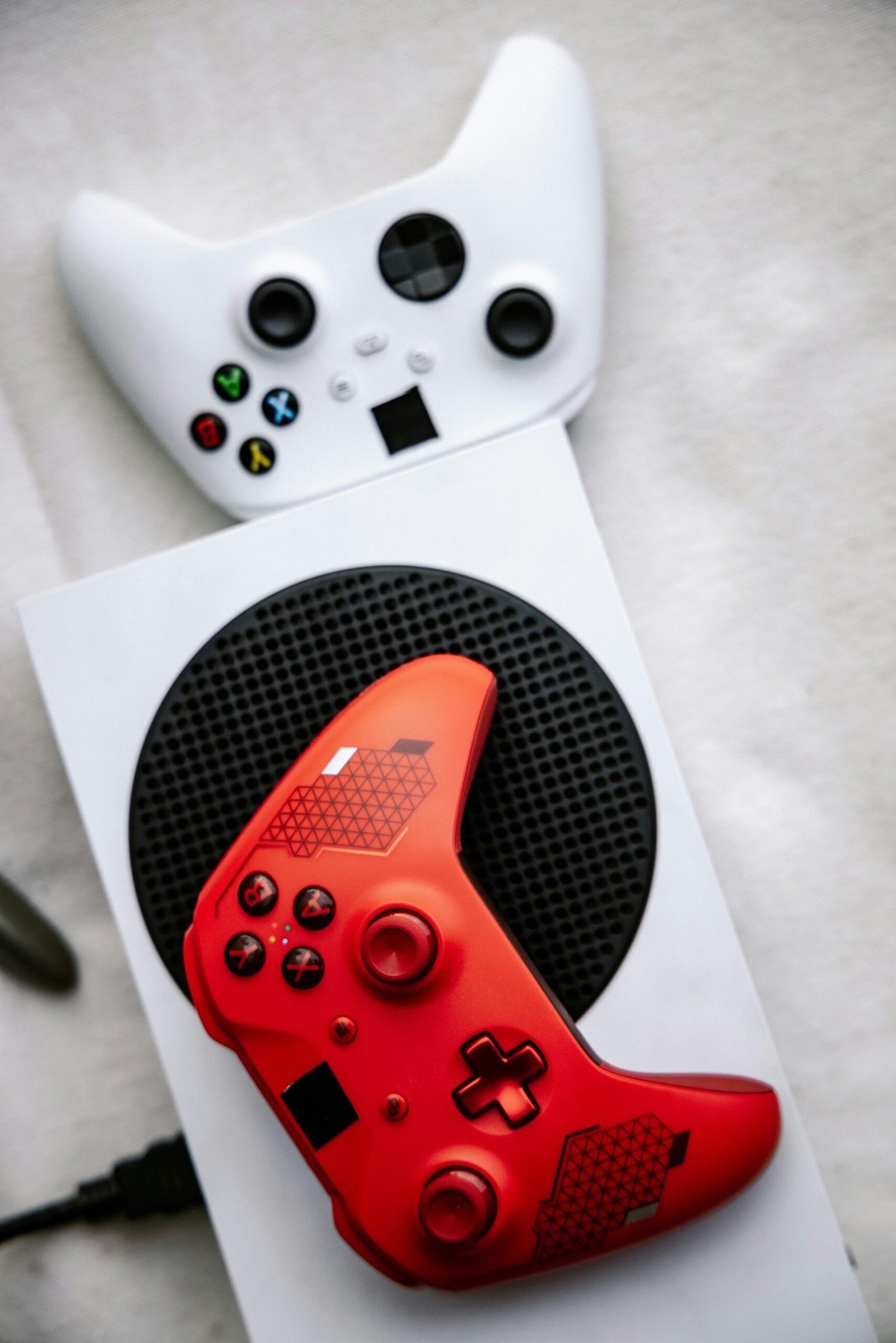 Red and white Xbox controllers with console, perfect for gaming content.