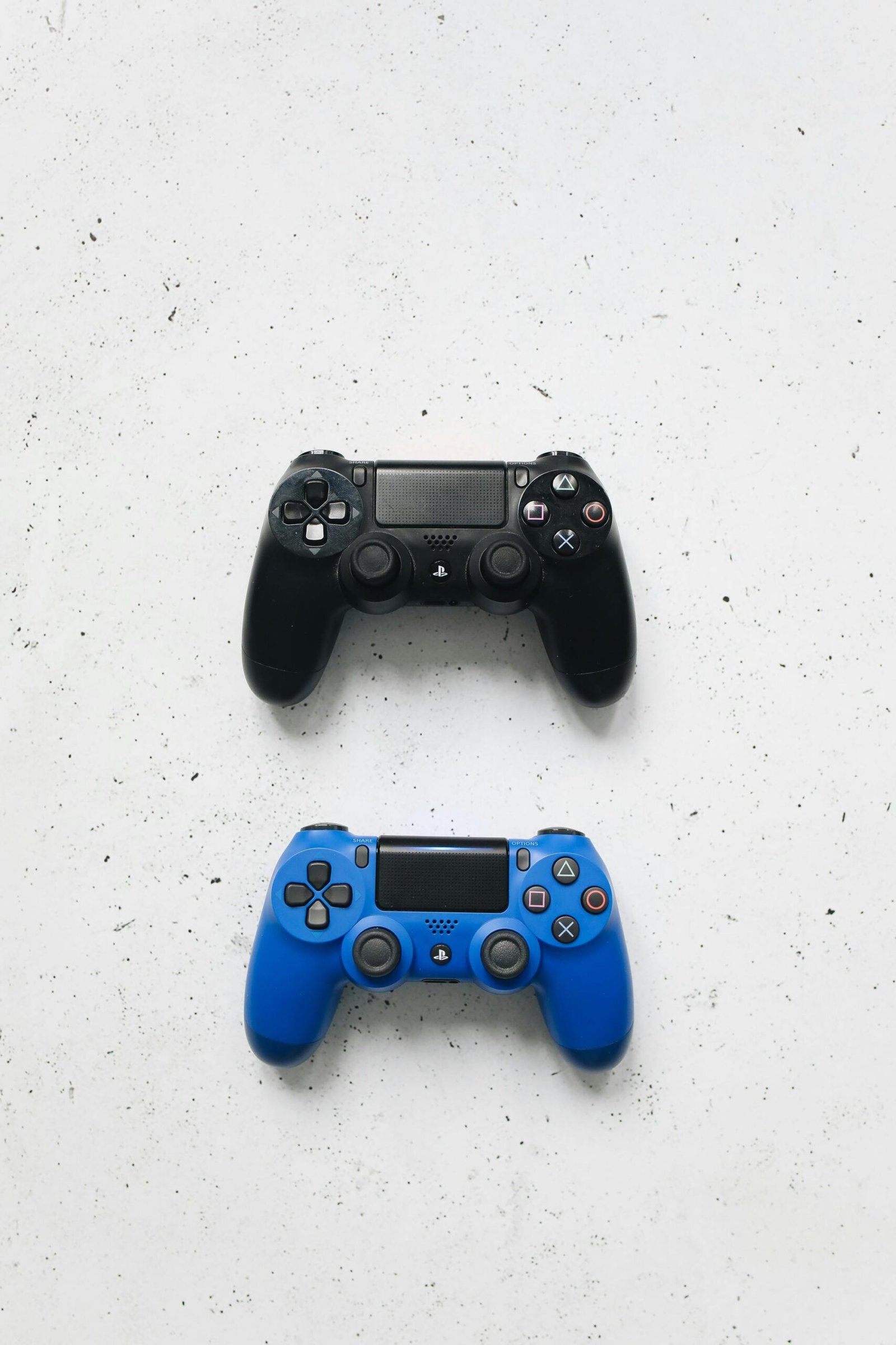 Top view of two gaming controllers, one black and one blue, on a white surface.